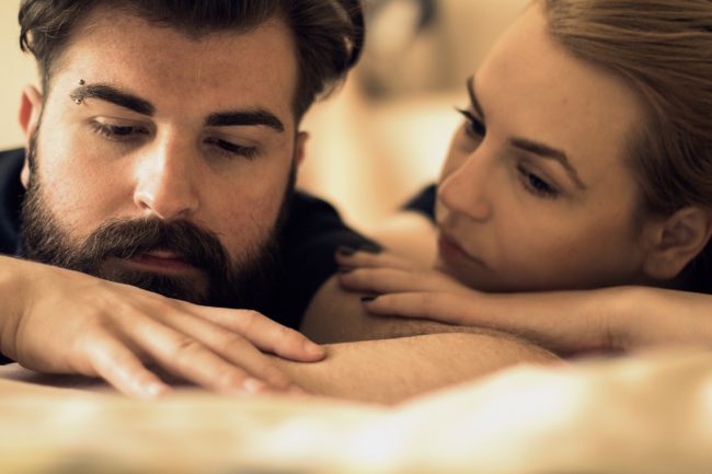 Unhappy young heterosexual couple in bedroom